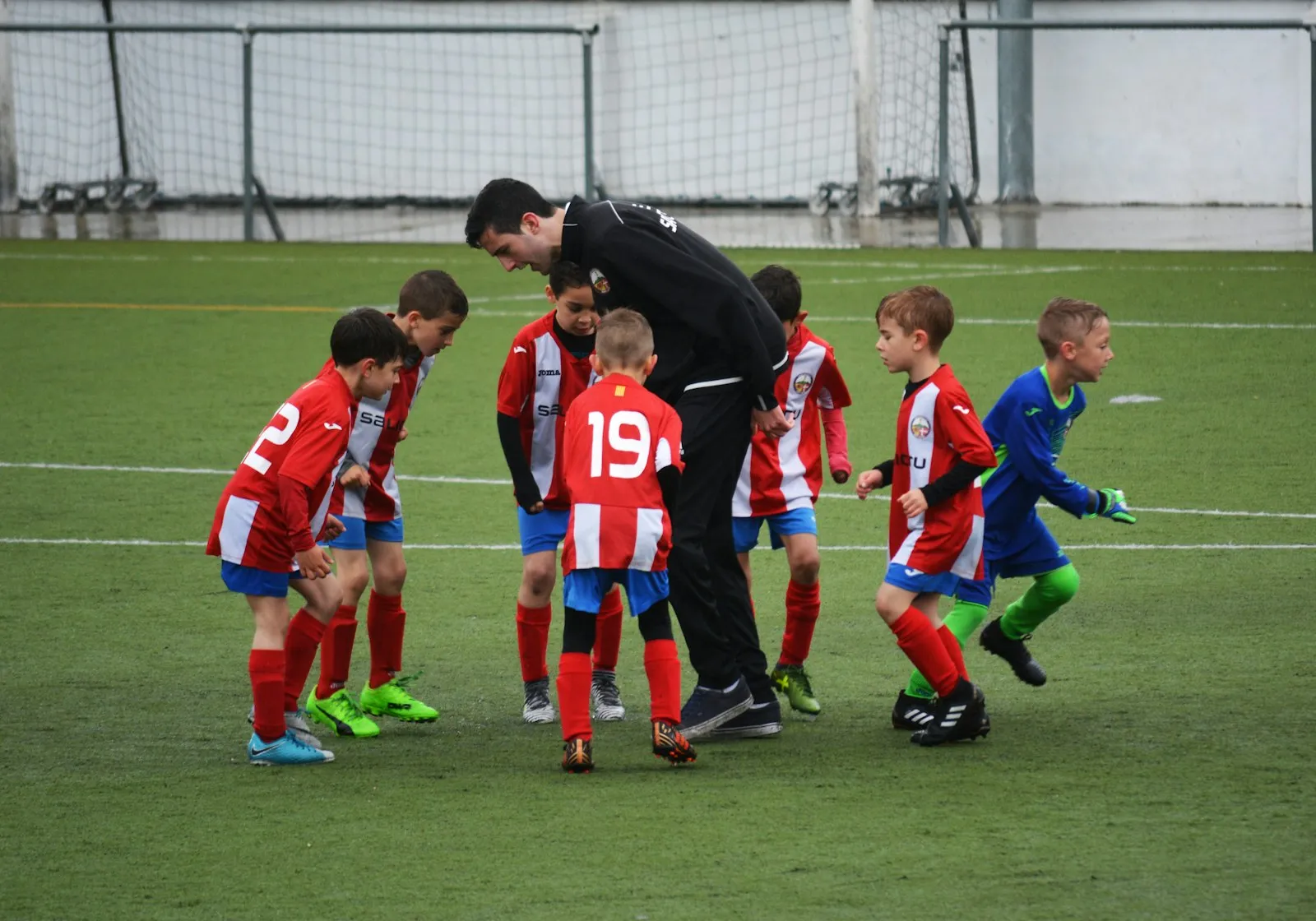 Entraînement de jeunes footballeurs avec leur entraîneur, illustrant le temps gagné par les bénévoles grâce aux inscriptions en ligne